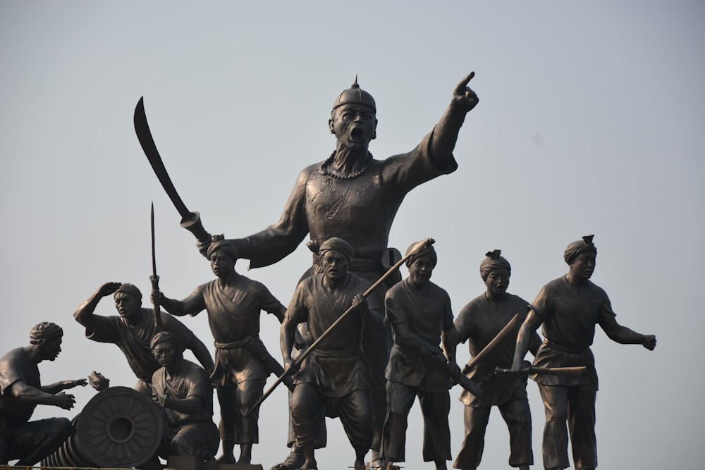 una estatua de un hombre sosteniendo una espada y rodeada de otras estatuas