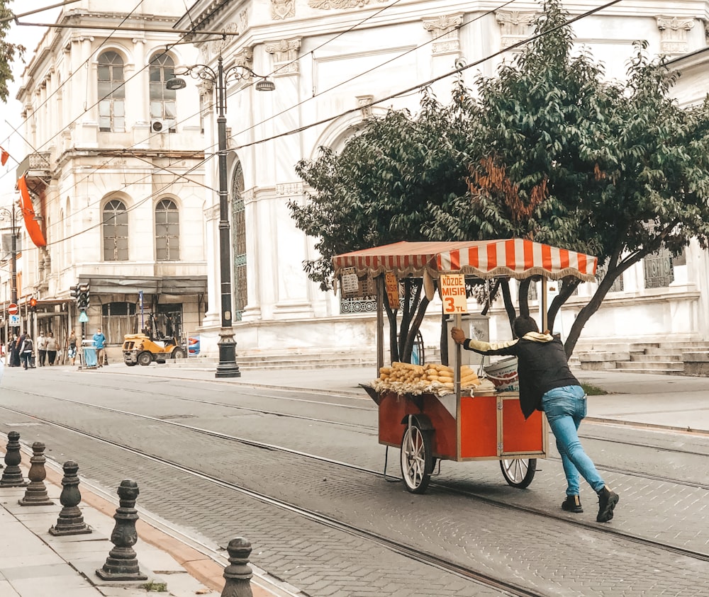 people riding on red and black auto rickshaw on road during daytime