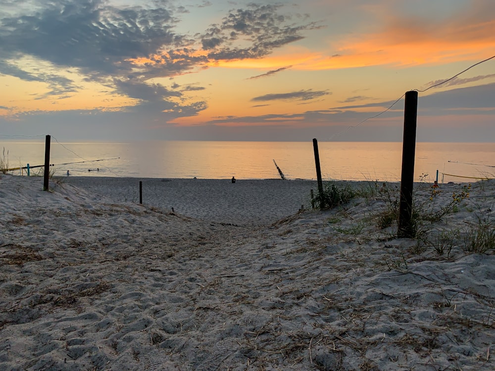 brown wooden poles on white sand beach during sunset