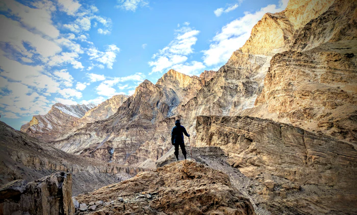 Randonneur en veste noire sur une montagne de roches brunes au Ladakh