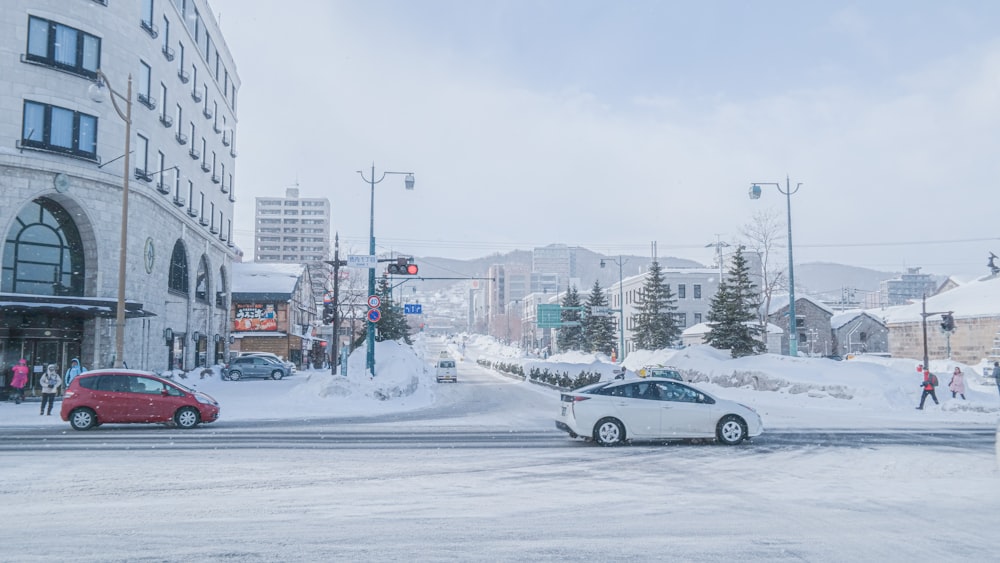 a red car driving down a snow covered street