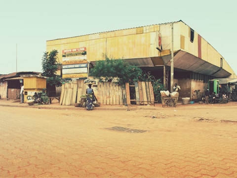 man in black jacket sitting on black motorcycle near brown building during daytime