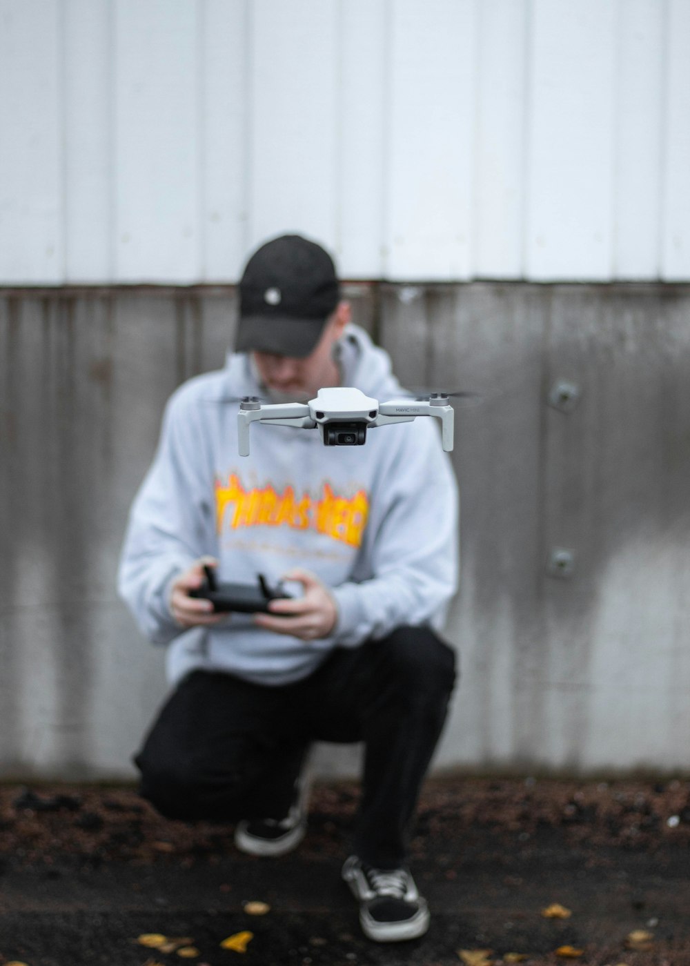 man in white hoodie and black pants sitting on brown wooden bench