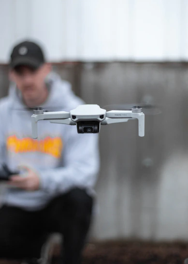 A sleek black and white portrait of a focused creative professional holding a drone controller.