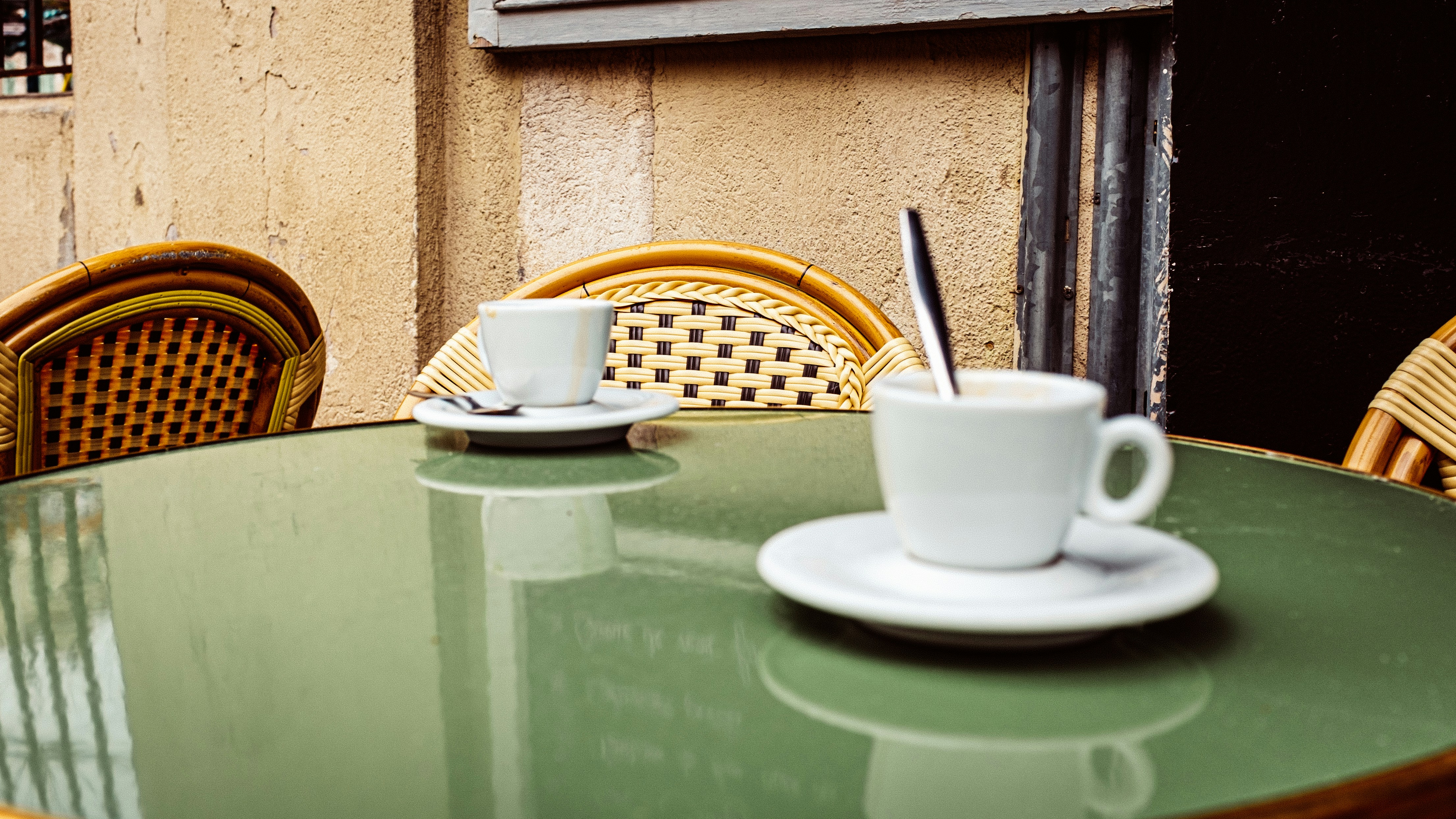 A person sitting alone at a café table, empty chair opposite, soft natural light, melancholic mood
