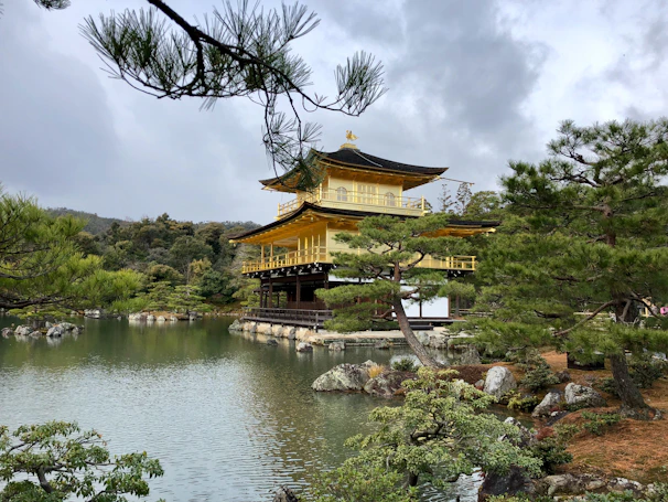 Golden temple spires reflecting in a tranquil pond under a clear sky.