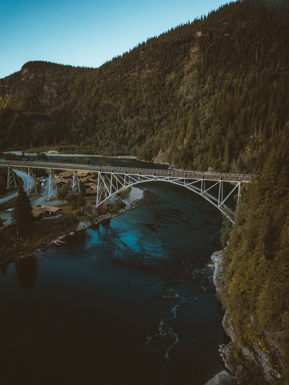 white bridge over river between green mountains during daytime