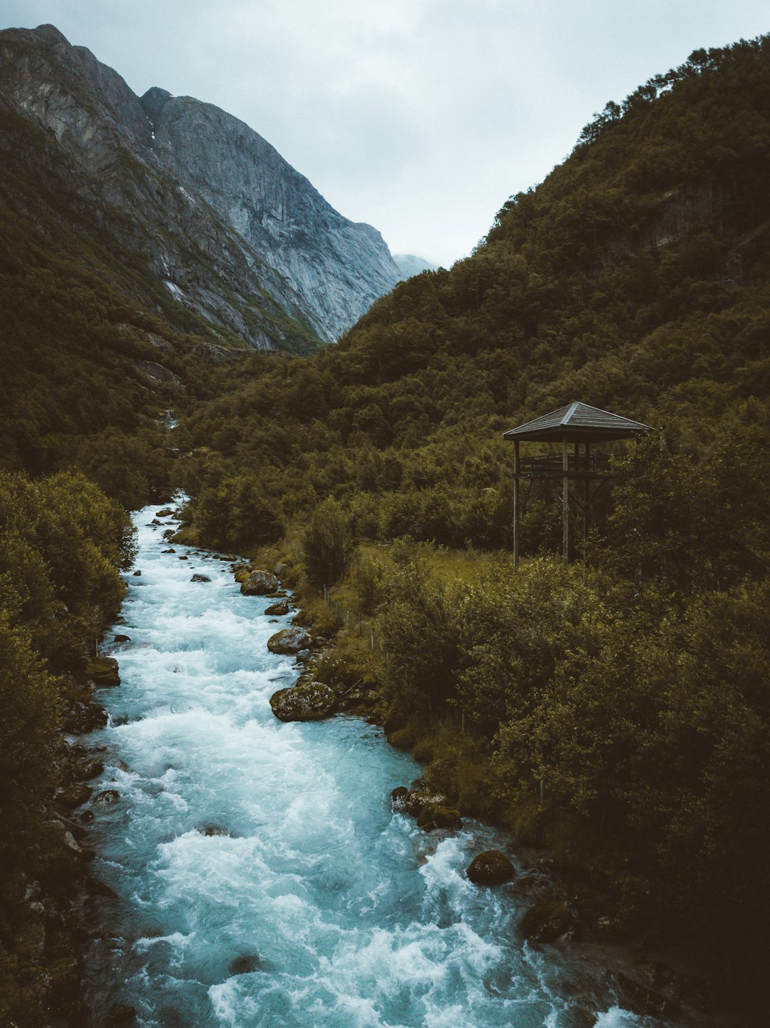 river in between green grass covered mountains during daytime