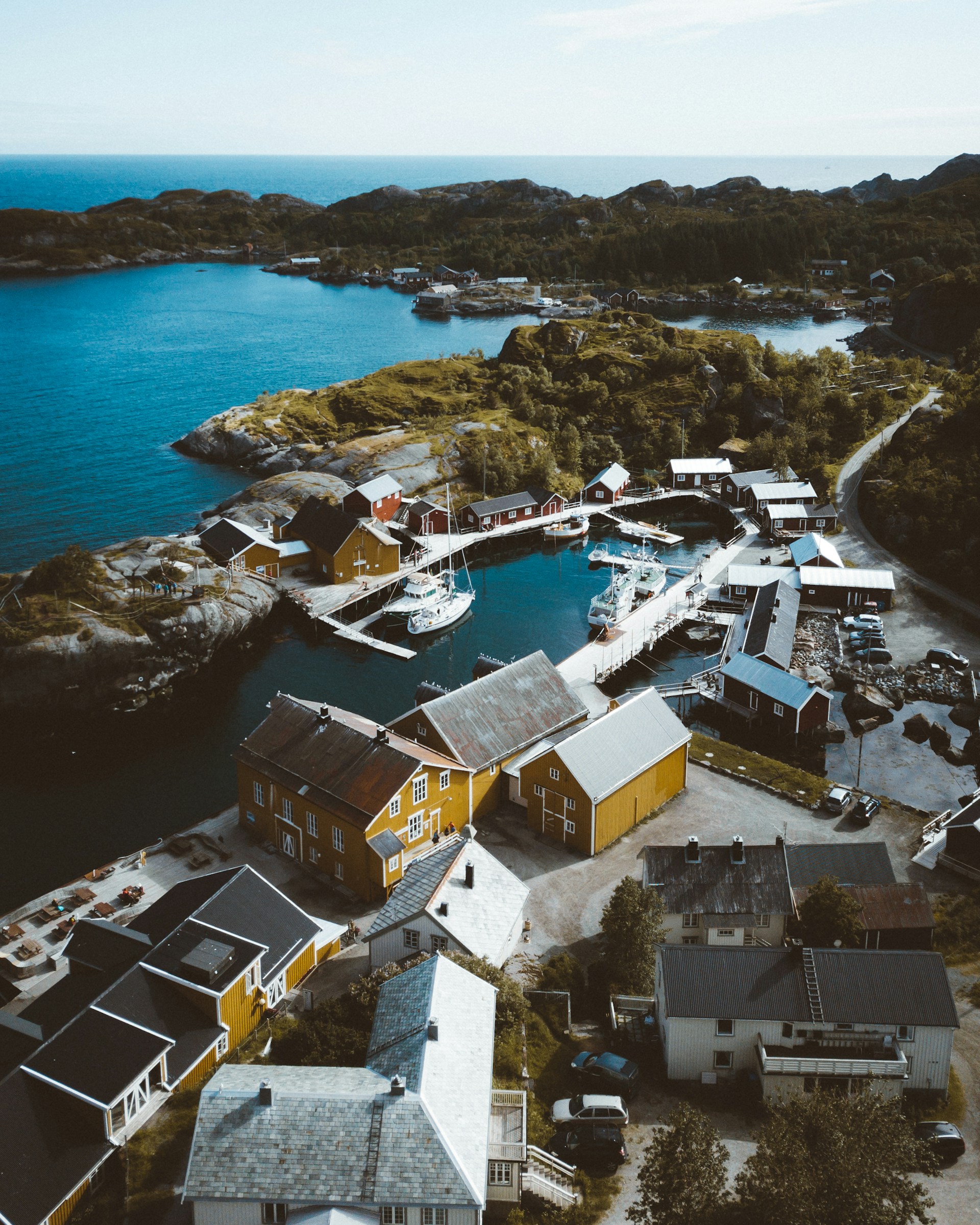 A serene aerial shot of a pastel-colored coastal village at sunrise, captured by drone.