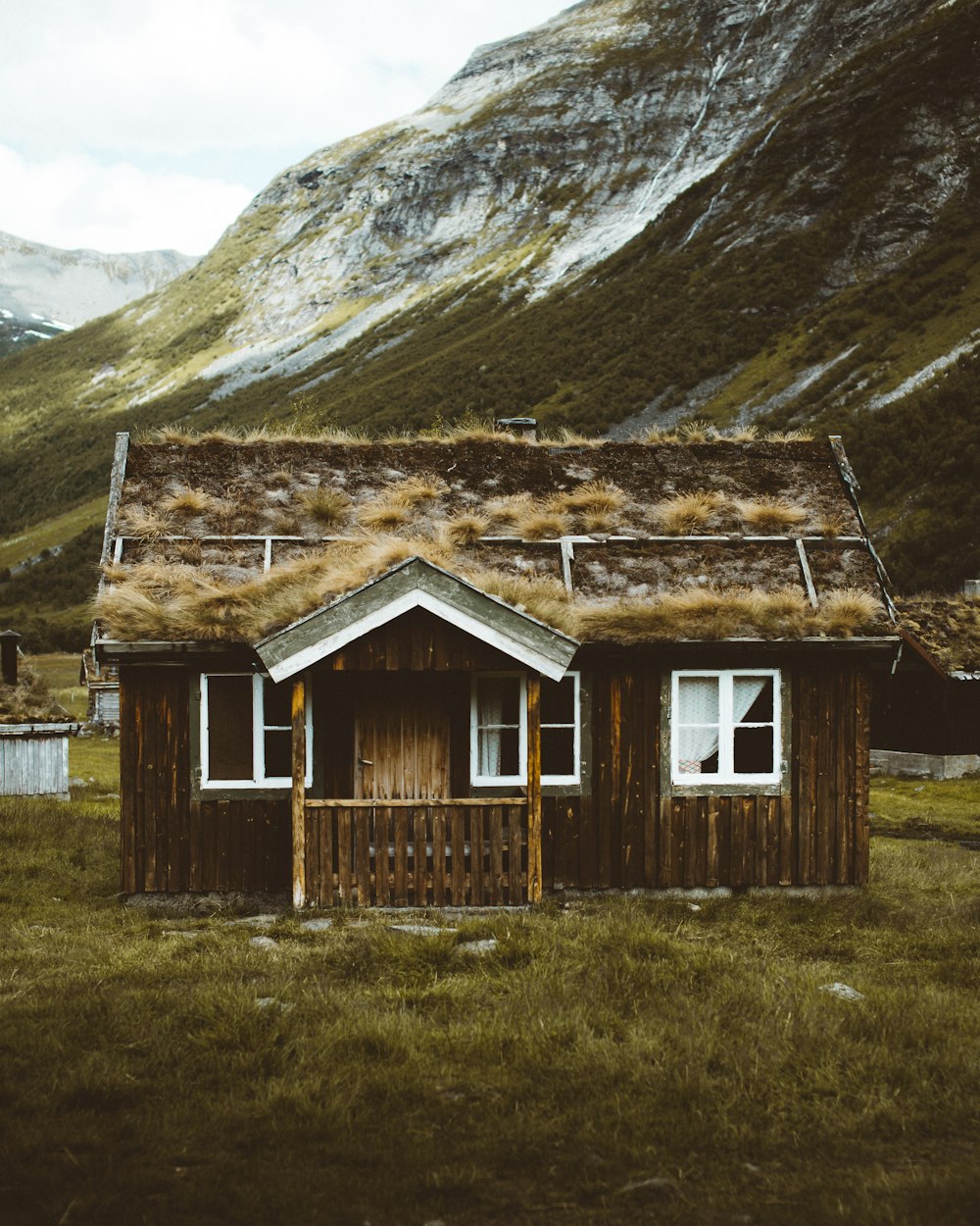 brown wooden house on green grass field near mountain