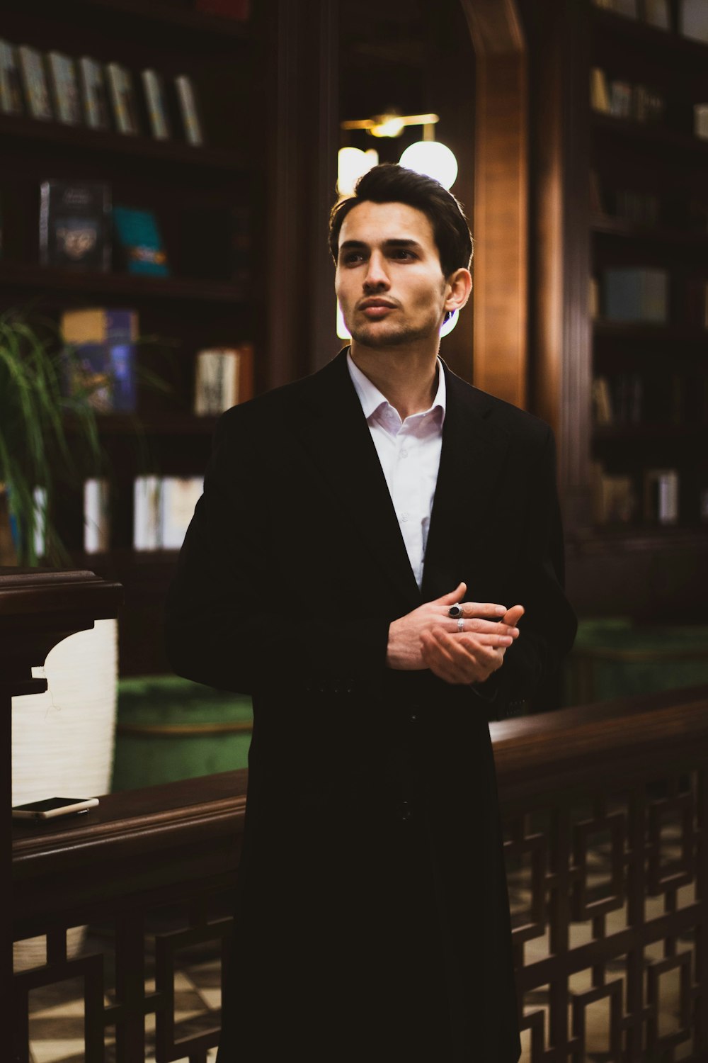 man in black suit standing near brown wooden table