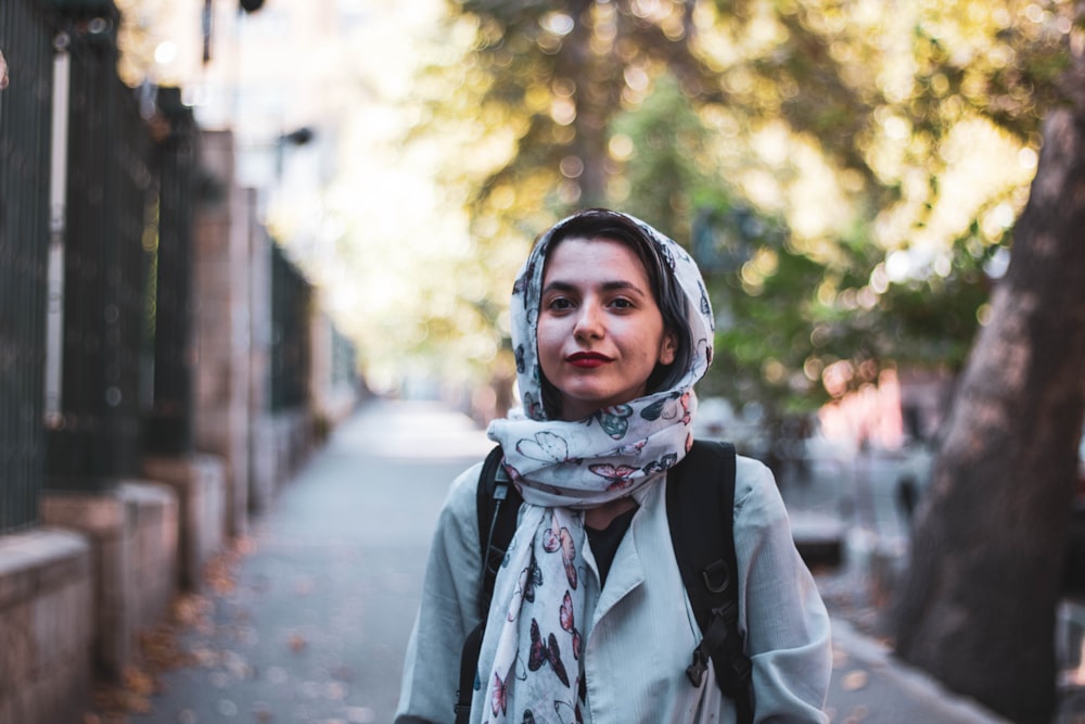 woman in gray and white scarf standing on road during daytime