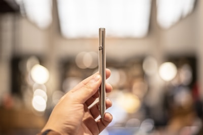 person holding silver tube type vape