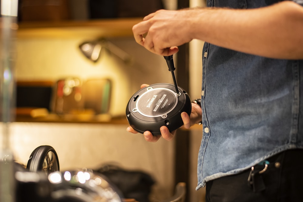 person in blue denim jeans holding black and gray corded headphones