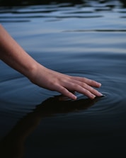persons hand on body of water
