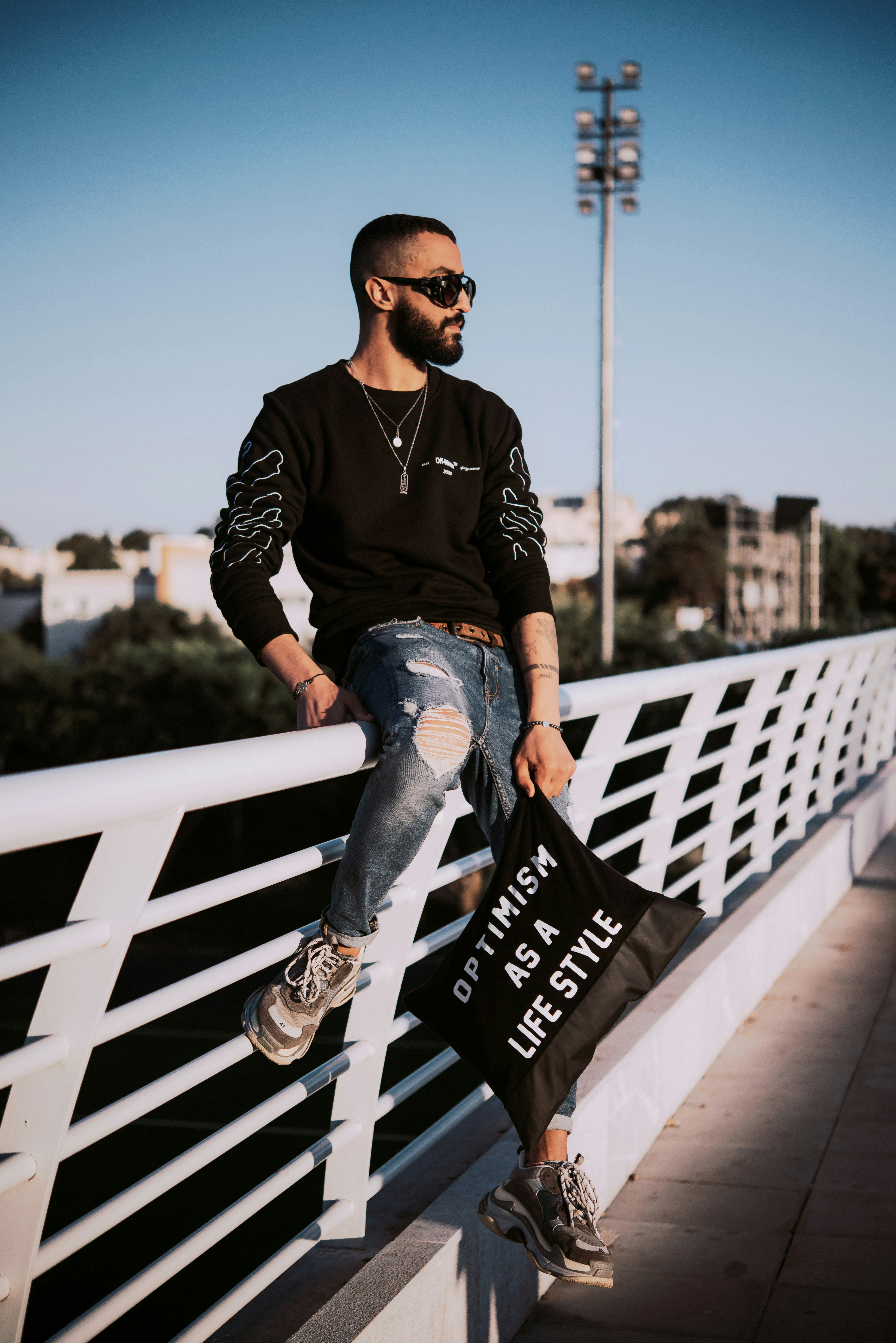 man in black and white long sleeve shirt and blue denim jeans sitting on white wooden