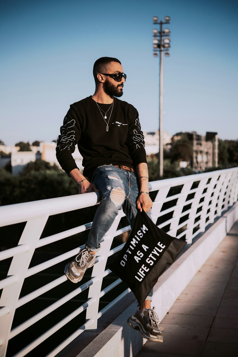 man in black and white long sleeve shirt and blue denim jeans sitting on white wooden