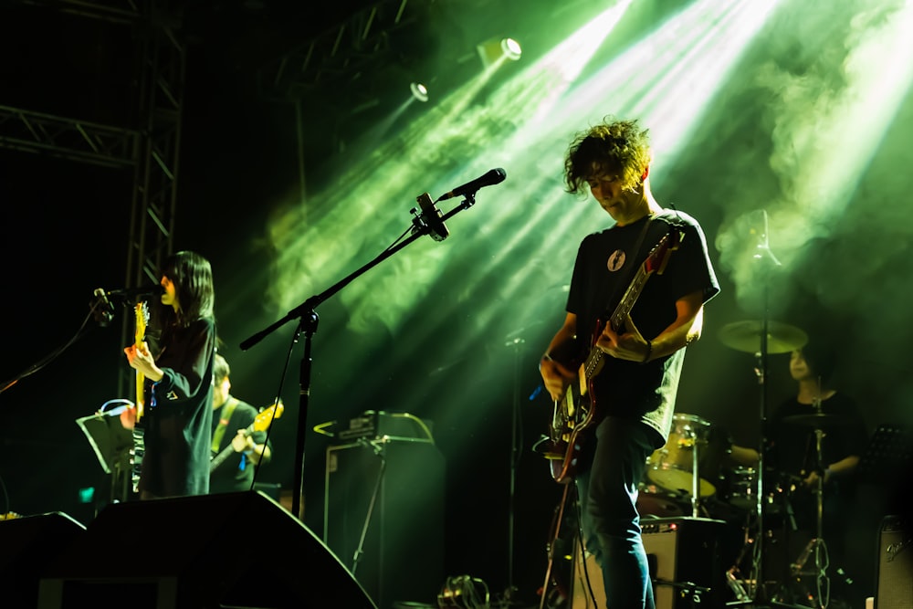 man in black crew neck t-shirt playing guitar on stage