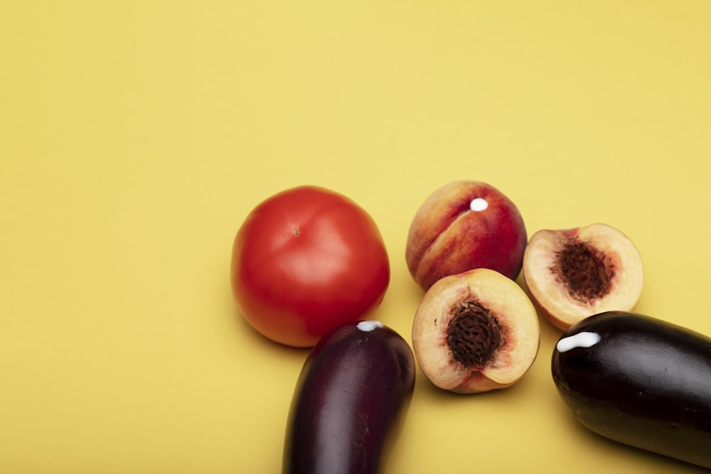 red apple fruit beside black round fruit