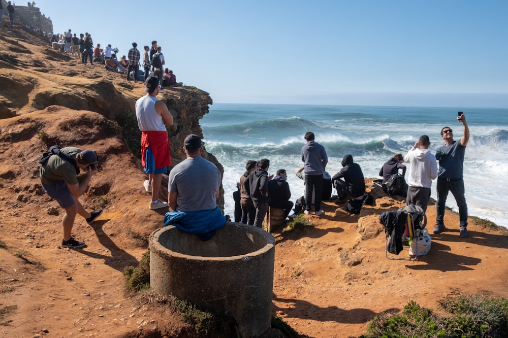 people standing on brown rock formation near body of water during daytime