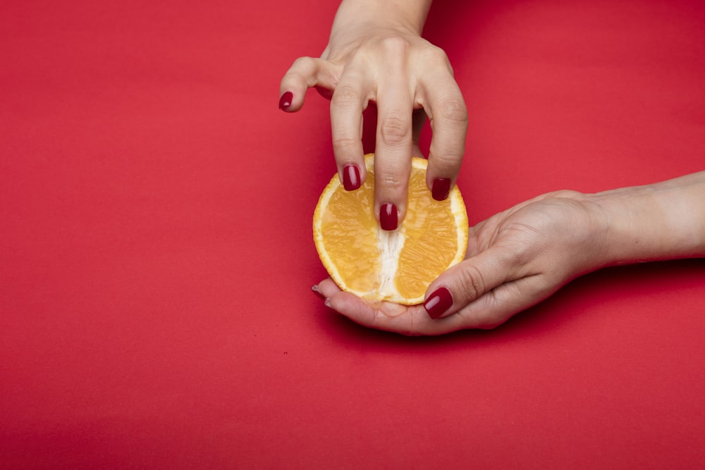 pessoa segurando a fruta laranja fatiada