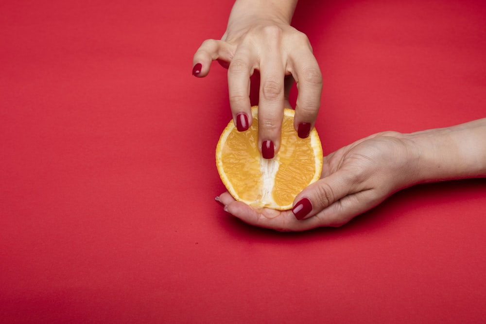 persona que sostiene fruta de naranja en rodajas