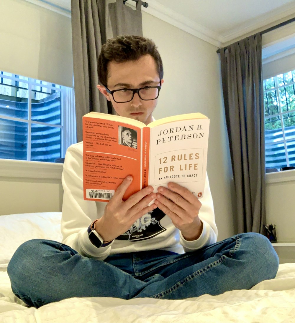 man in blue denim jeans reading book