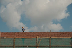 Close-up of hands fitting new tiles on a rooftop with tools laid out nearby.