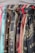 Multiple scarves are hanging in a row, displaying various patterns and colors. Each scarf appears to have printed designs, some with textual elements and others with intricate patterns. The colors of the scarves range from shades of blue and red to brown and teal.