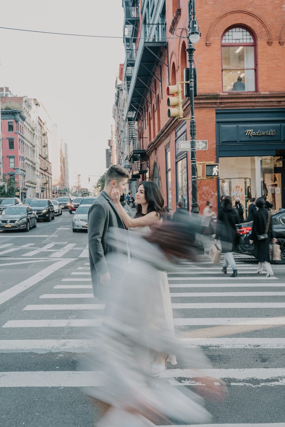 man in gray suit jacket holding woman in white wedding dress walking on pedestrian lane during