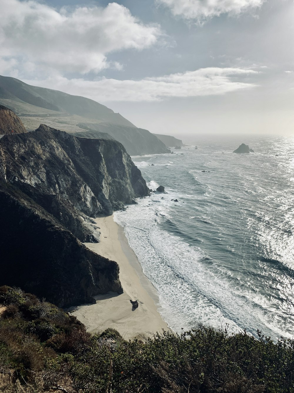 green and brown mountain beside sea during daytime