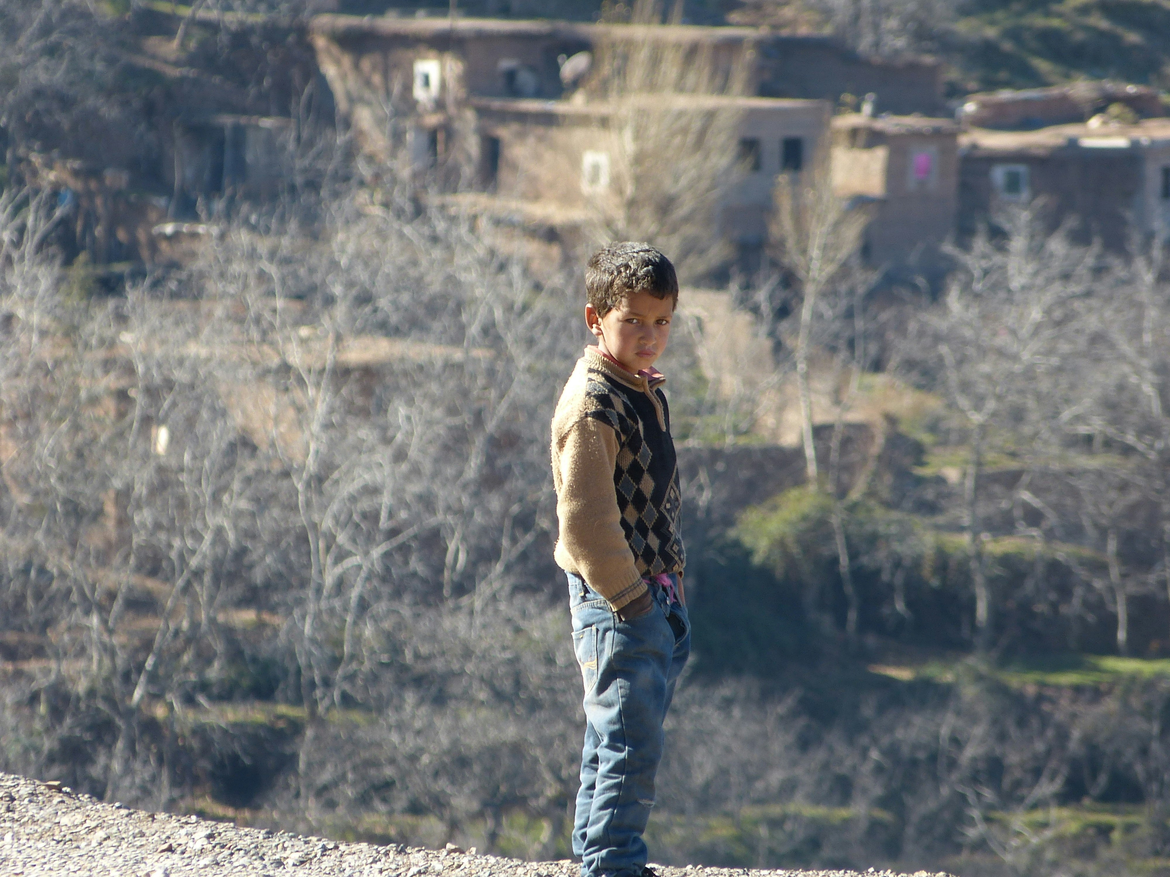 man in brown crew neck t-shirt and blue denim jeans standing on rock during daytime