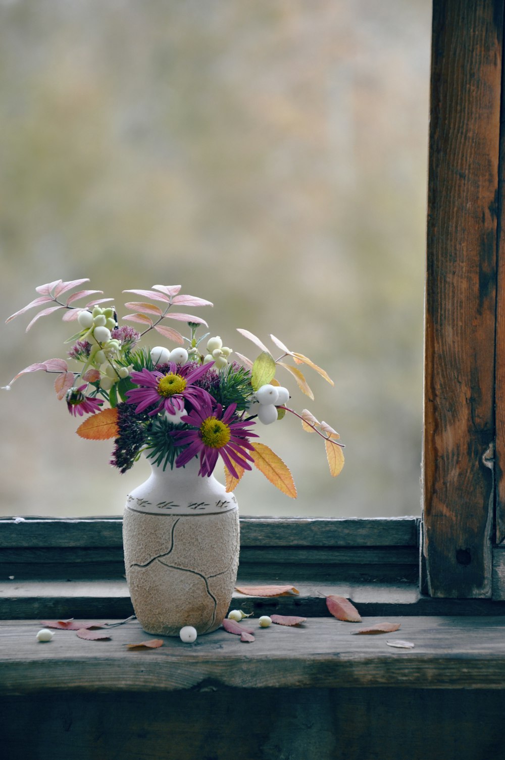 weiße und gelbe Blumen in grauer Vase auf braunem Holztisch