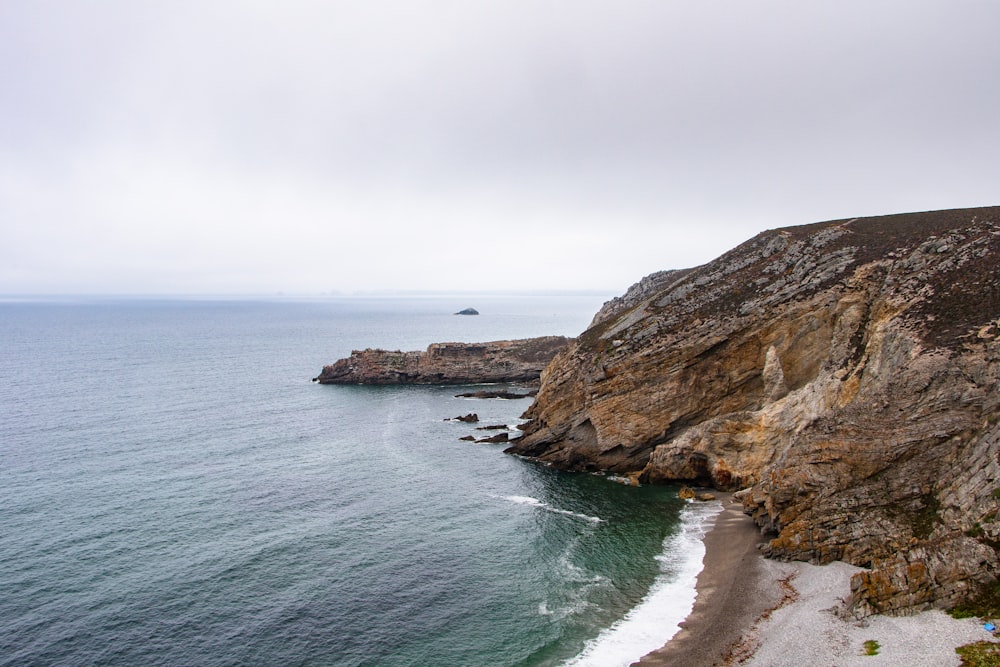 brown rock formation on sea under white sky during daytime