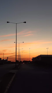 Installation team setting up LED streetlights along a quiet town road during sunset