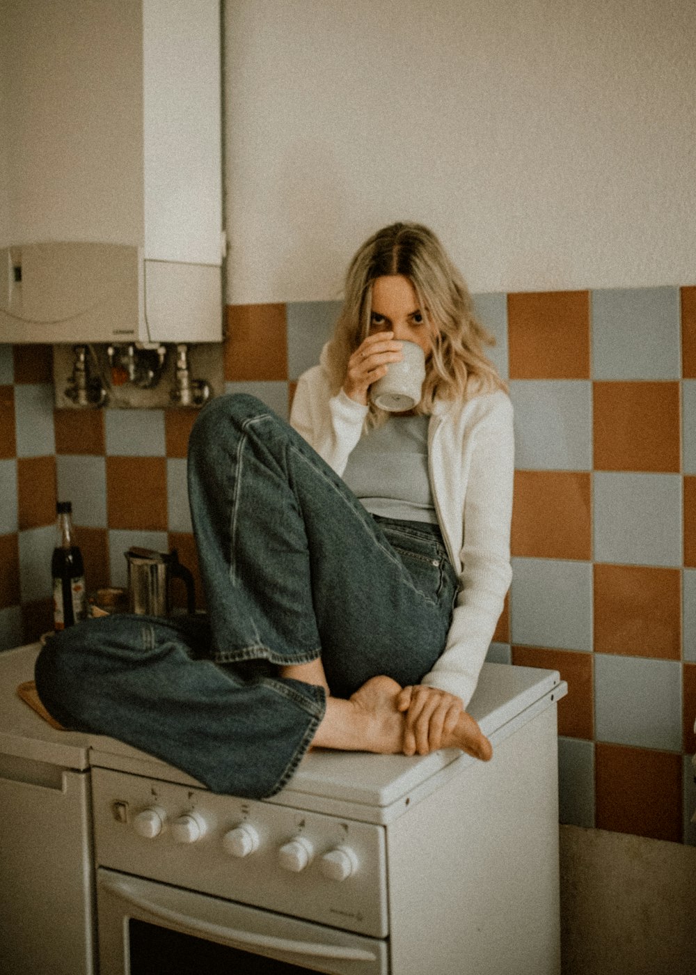 Mujer con camisa blanca de manga larga y jeans de mezclilla azules sentada en la silla