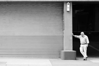 man in white long sleeve shirt and black pants walking on sidewalk during daytime