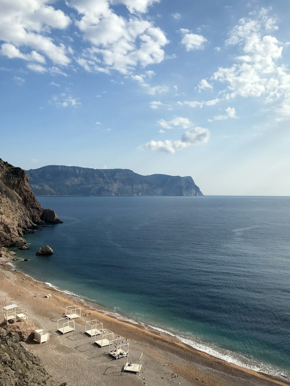 blue sea beside brown mountain under blue sky during daytime