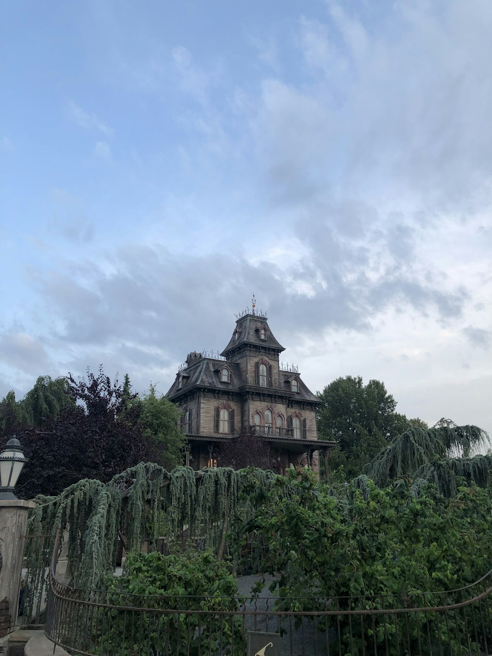 bâtiment en béton brun et blanc entouré d’arbres verts sous des nuages blancs et un ciel bleu pendant