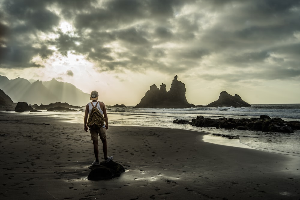 hombre con camisa blanca de pie en la playa durante el día