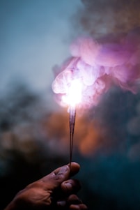 person holding lighted sparkler in close up photography