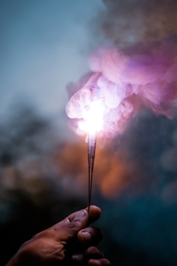 person holding lighted sparkler in close up photography