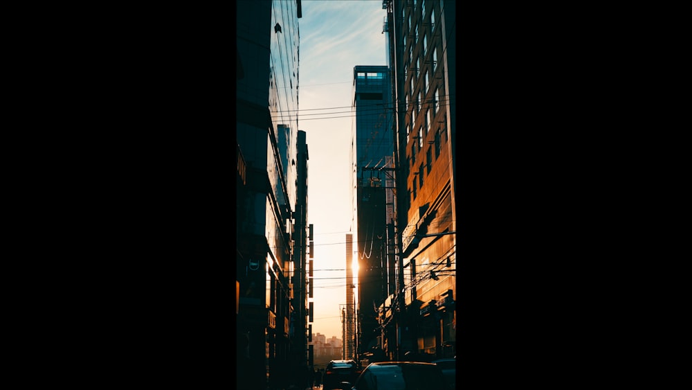 cars parked on side of the road in between high rise buildings during night time