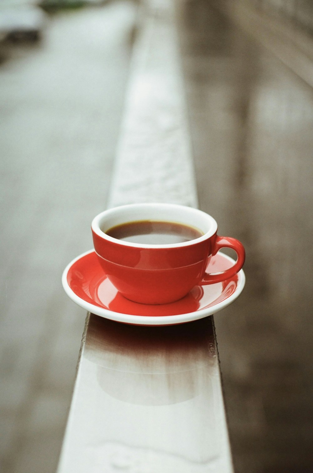 red ceramic teacup on red saucer on brown wooden table