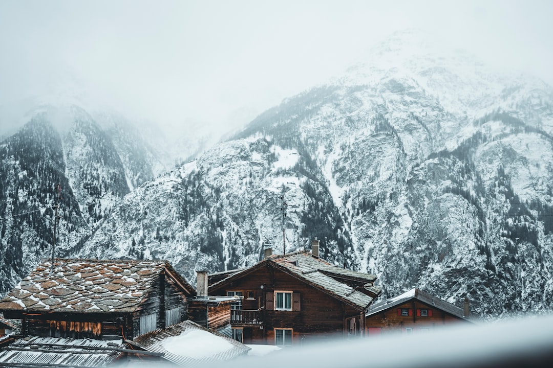 brown wooden houses near snow covered mountain during daytime