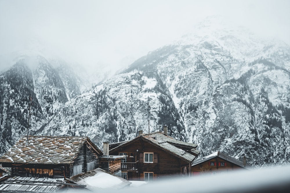 brown wooden houses near snow covered mountain during daytime
