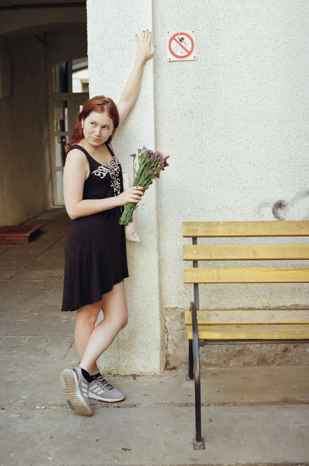 Femme en robe noire à bretelles spaghetti tenant un bouquet de fleurs