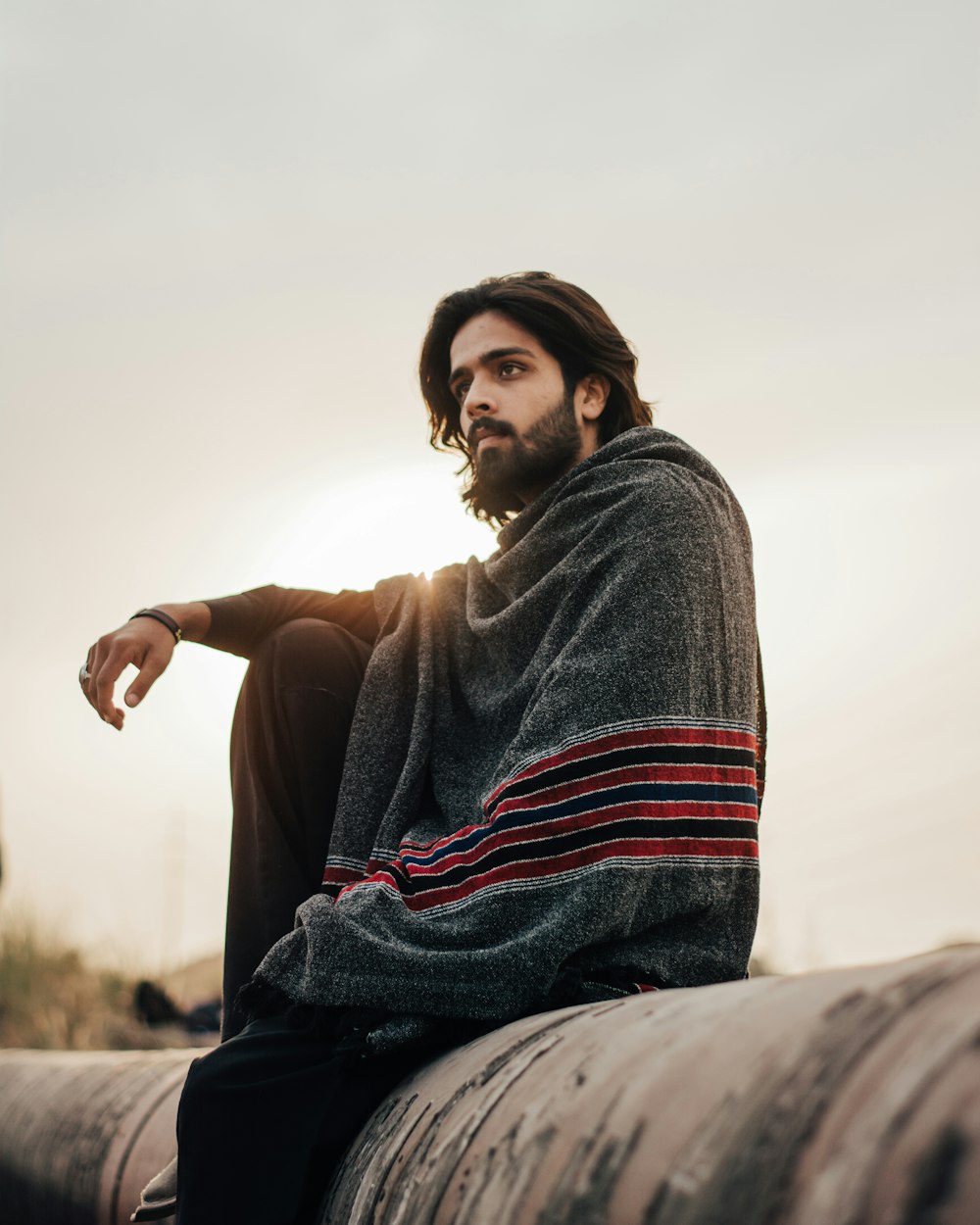 woman in gray sweater sitting on rock during daytime