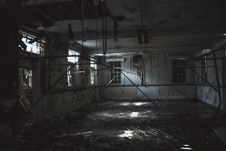 A dimly lit abandoned theater stage with scattered debris and faint shadows.