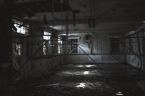 A dimly lit abandoned theater stage with scattered debris and faint shadows.